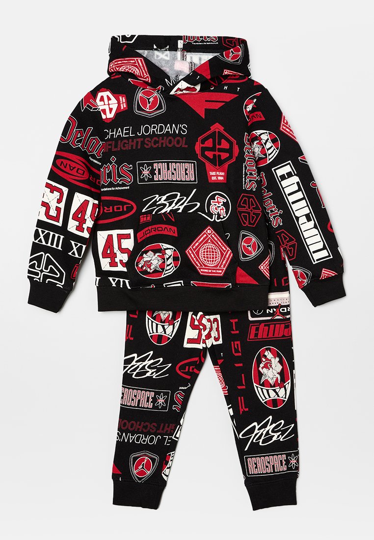 Set di felpa nera con cappuccio e pantaloni, caratterizzato da vari loghi grafici rossi e bianchi, realizzato in un tessuto morbido e strutturato con una vestibilità comoda.