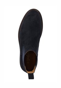 Zapato de ante azul oscuro con una textura suave, paneles laterales elásticos y una suela marrón en contraste. El interior tiene un forro de cuero color beige y un logo.