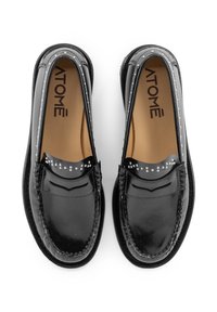 Mocassini in vernice nera con design a mocassino. Presentano decorazioni di piccoli chiodini argentati sulla parte superiore. Suola testurizzata.