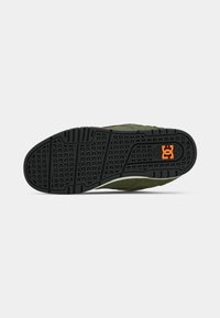Green suede skate shoe with a textured black rubber sole. Features a small orange logo on the heel. Simple design and low profile.