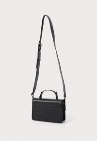 Sac à main en cuir noir avec une forme structurée, une poignée supérieure et une bandoulière ajustable. Il dispose d'un fermoir à rabat et d'un détail de logo subtil.