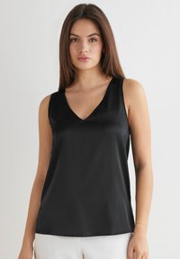Schwarzes ärmelloses Top aus glattem Stoff mit einem V-Ausschnitt, versehen mit einem neutralen Saum und einer taillierten Silhouette, ideal zum Überziehen oder zum alleinigen Tragen.