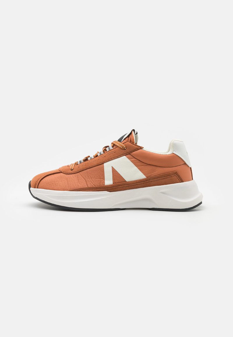Orange og hvid sneaker med en tekstureret overdel, der har et slankt design, rund tå og en hvid, polstret sål. Stribede snørebånd fremhæver.