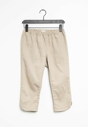 Beige tapered broek gemaakt van een zachte, lichte stof. Beschikt over een elastische tailleband en een zoom met kleine zijsplitten. Hangt aan een zwarte hanger.