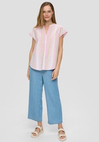 Leichte, gestreifte Bluse in Pink und Weiß, kurzärmlig, V-Ausschnitt mit A-Linien-Form, kombiniert mit lockeren blauen Denim-Hosen.