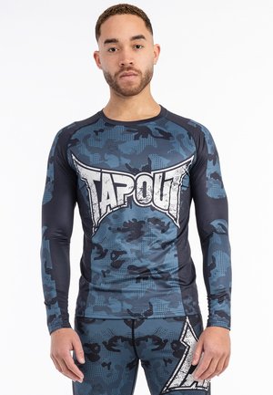Langærmet atletisk skjorte i marineblå og grå camouflage, med et stort hvidt "TAPOUT"-logo på forsiden og et åndbart stofdesign.