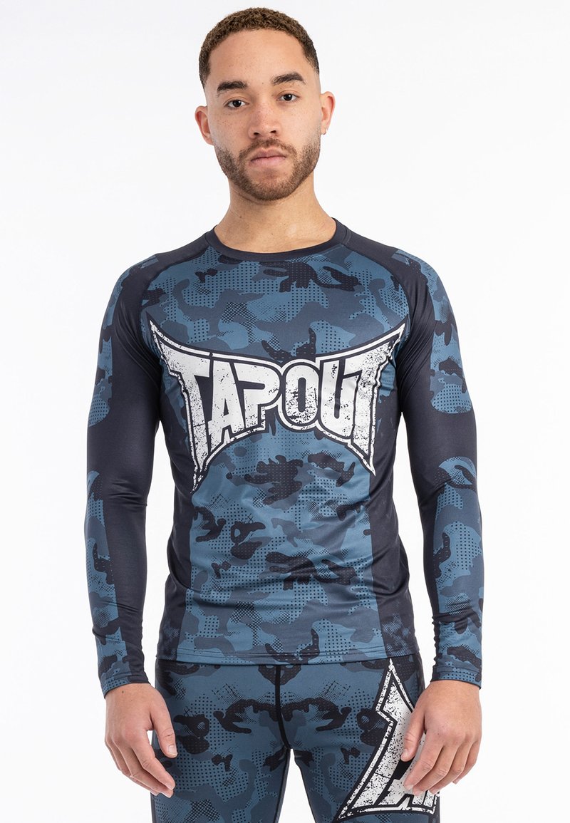 Hosszú ujjú sportpóló tengerészkék és szürke álcázásban, nagy fehér "TAPOUT" logóval az elején és lélegző anyag kialakítással.