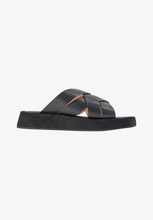 Sandales à enfiler en cuir noir avec des brides tissées, une semelle intérieure au toucher doux et texturé, et une semelle extérieure plate et noire robuste. Design minimaliste avec des détails d'accent.