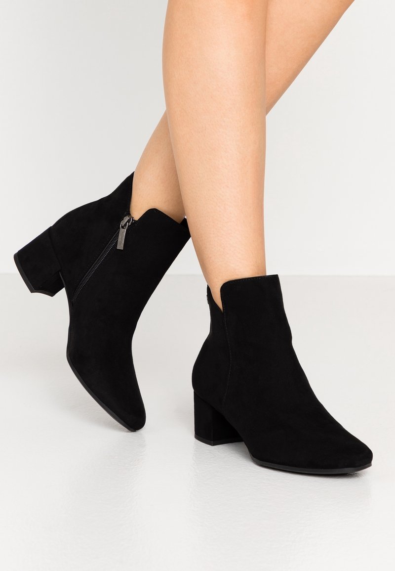 Černé semišové kotníkové boty s špičatou špičkou a střední blokovou podpatkou. Obsahují boční zip a scalloped otvor.