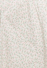 Valkoinen kangas, jossa on toistuva kuvio pieniä vaaleanpunaisia kukkia vihreillä lehdillä, esittelee herkän kukkakuosin.