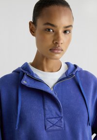 Navyblauwe hoodie met rits van katoen, voorzien van een capuchon, trekkoorden en een voorpaneel met een gestikte driehoekdetail.