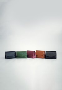 Fünf Leder-Clutch-Taschen in Schwarz, Grün, Burgunder, Braun und Schwarz. Jede Tasche hat ein umklappbares Klappen-Design mit glatter Textur.