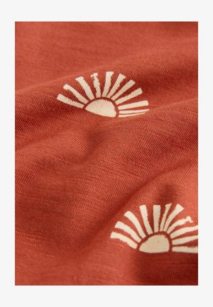 Terakotová látka s motívom slnečných lúčov v krémovo bielej farbe, charakterizovaná jemnou textúrou s jemným leskom a viditeľnou štruktúrou tkania.