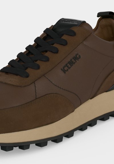 Baskets en cuir et daim marron avec semelle beige, lacets noirs et logo "ICEBERG" sur le côté.