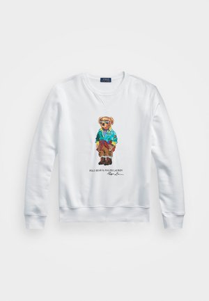 Felpa bianca con colletto tondo e polsini a coste, che presenta un orso colorato ricamato con una giacca blu e occhiali da sole.