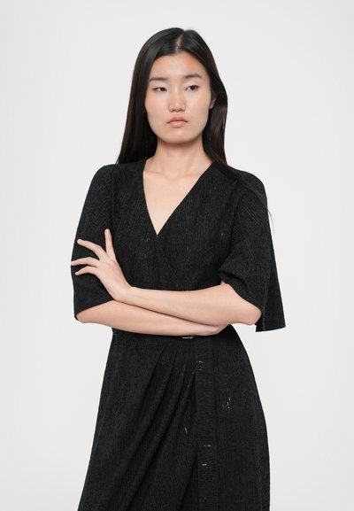 Black dress with short sleeves, featuring a textured fabric and V-neckline. Designed with a wrap style and pleated detail at the waist.
