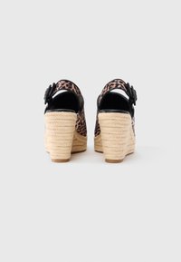 Πέδιλα με τακούνι σε λεοπάρ μοτίβο με μαύρες λεπτομέρειες, πλεκτή πλατφόρμα από τζούτ και λουράκι στον αστράγαλο με στρογγυλή αγκράφα.