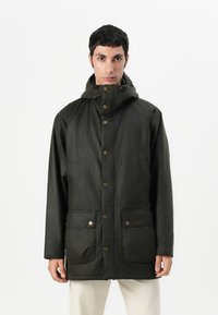 Σκούρο πράσινο αδιάβροχο μπουφάν με ψηλό γιακά, κουμπιά που κουμπώνουν και δύο μπροστινές τσέπες. Διαθέτει λεία υφή και χαλαρό σχέδιο.