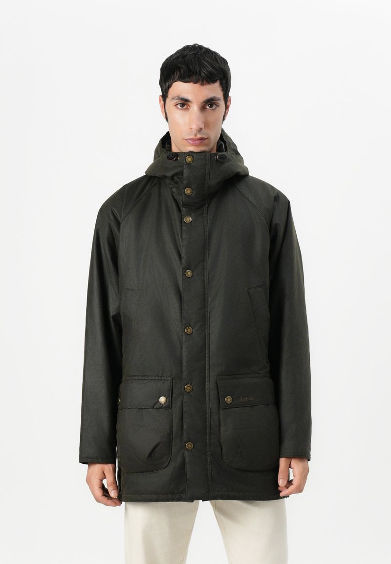Σκούρο πράσινο αδιάβροχο μπουφάν με ψηλό γιακά, κουμπιά που κουμπώνουν και δύο μπροστινές τσέπες. Διαθέτει λεία υφή και χαλαρό σχέδιο.