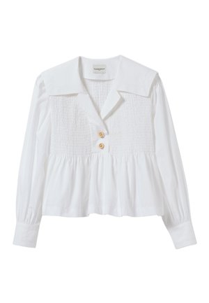 Blouse blanche avec un large col, un devant froncé et une taille smockée. Elle possède deux boutons dorés et des manches longues avec des détails de poignets.