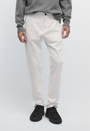 Witte katoenen broek met een rechte pasvorm, voorzien van een klassieke vijf-pocket ontwerp en gecombineerd met donkere suède schoenen.