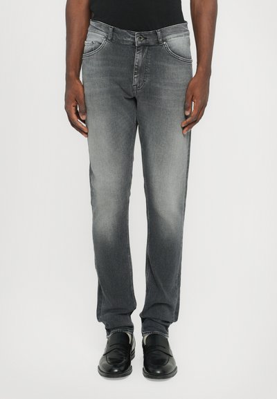 Szare dżinsy typu slim fit, z niewielkimi przetarciami, czterema kieszeniami i zapięciem na zamek. W połączeniu z czarnymi skórzanymi loafersami.