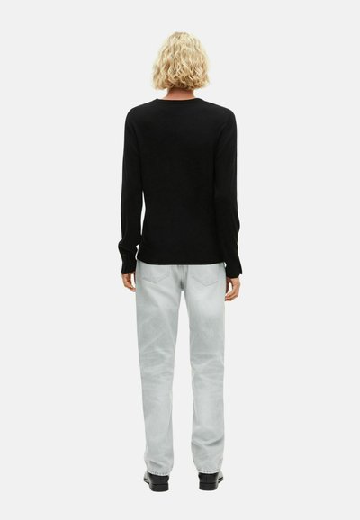 Top negro de manga larga con escote redondeado, combinado con jeans rectos de color gris claro. Textura suave y diseño casual.