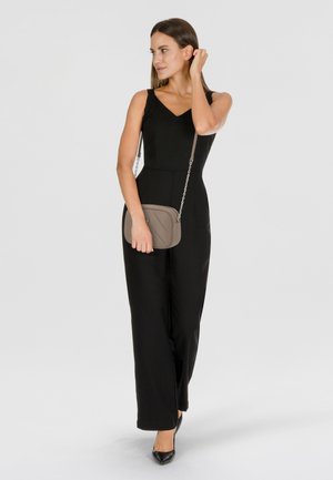 Tuta nera con corpino aderente, scollatura a V e gambe larghe. Abbinata a una borsa a tracolla taupe con tracolla a catena e décolleté nere con punta.