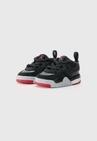 Chaussures de sport noires et grises avec des accents rouges. Caractéristiques en suède et en maille, design lacé et semelles en caoutchouc avec une adhérence texturée.