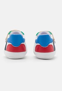Wielokolorowe sneakersy na białej podeszwie, z niebieskimi, czerwonymi i zielonymi akcentami, gładką skórzaną fakturą oraz zapięciem na rzep.