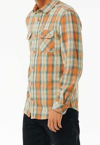Camicia a quadri nei colori arancione, blu e bianco; presenta due tasche sul petto, maniche lunghe, chiusura con bottoni e una texture di tessuto a motivo.