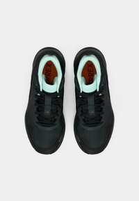 Μαύρα αθλητικά παπούτσια με υφή στο επάνω μέρος, λεπτομέρειες σε μέντα πράσινο και καφέ εσωτερική σόλα. Διαθέτουν σύστημα κορδονιών και ενισχυμένη μύτη.