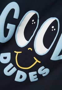 Camiseta de algodón azul marino con el texto en un atrevido azul claro "COOL" acompañado de grandes ojos y una boca amarilla sonriente, y "DUDES" en azul claro a juego debajo.