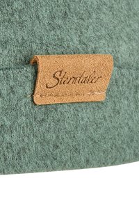 Green textured fabric with a brown leather tag featuring the name "Sterntaler," stitched with a light thread.