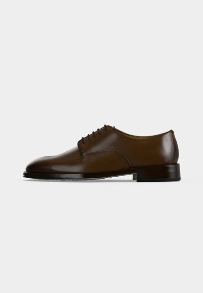 Chaussure habillée en cuir marron pour homme avec laçage fermé, petit talon et surface lisse et polie, montrée de profil sur un fond uni.