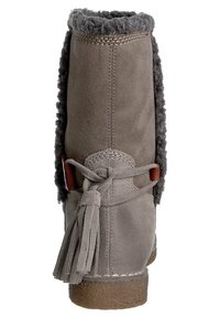 Bota de tobillo de ante gris con forro de piel de oveja, detalle de flecos y un acento de cuero. Cuenta con una suela texturizada para mayor agarre y durabilidad.