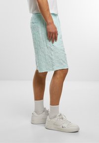Lyseblå teksturerede shorts med et mønster, elastisk talje og sidelommer, båret med hvide sneakers og ankel-lange hvide sokker.