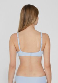 Světle modrý podprsenka s nastavitelnými ramínky, bez švů, a zapínáním na háček. Hladký materiál s minimálními detaily.