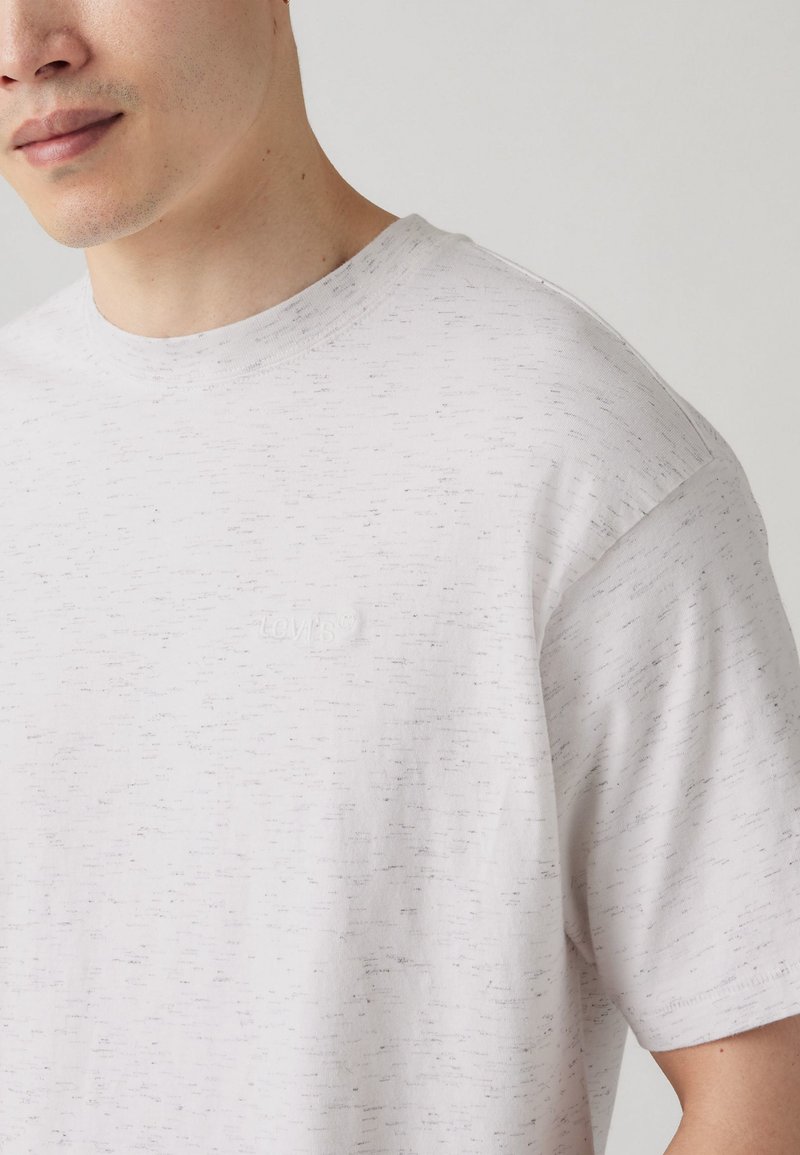Hellgraues T-Shirt aus strukturiertem Stoff, mit Rundhalsausschnitt und kurzen Ärmeln. Kleines prägtes Logo auf der Brust.