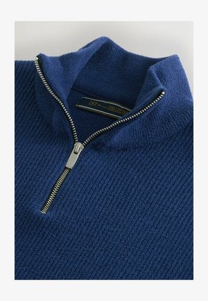 Granatowy polar z półrozpinanym kołnierzem, z teksturowaną ryżową powierzchnią oraz srebrnym zamkiem błyskawicznym z metalowym uchwytem.