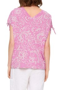 Rosa Kurzarmoberteil mit floralem Muster, V-Ausschnitt hinten und seitlichen Bindebändern. Hergestellt aus leichtem Material, mit lockerer Passform.