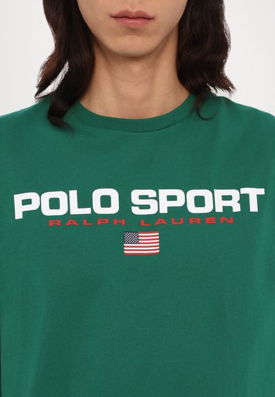 Camiseta de algodón verde con "POLO SPORT" en letras blancas en negrita, "RALPH LAUREN" en rojo y un pequeño gráfico de la bandera estadounidense.