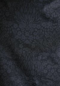 Tessuto scuro con motivo floreale in diverse tonalità di grigio. Il design include sagome di fiori e foglie, creando profondità e texture.