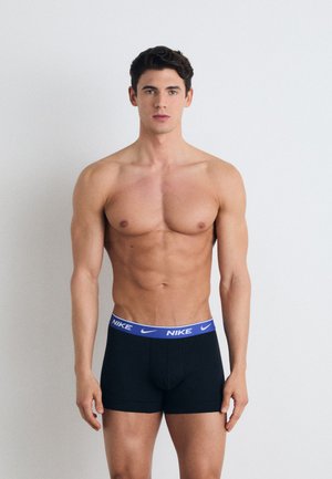 Boxer briefs neri elasticizzati con un elastico blu con il marchio Nike, presentano un design aderente e una texture liscia. Il modello sta in piedi su uno sfondo chiaro.