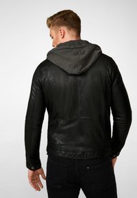 Schwarze Lederjacke mit grauem Kapuzenkragen, zeichnet sich durch ein tailliertes Design, sichtbare Nähte und eine glatte Textur aus. Die Rückansicht zeigt Details an den Schultern.