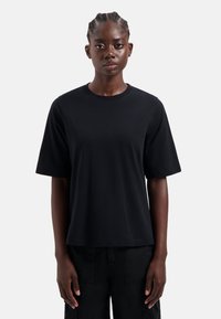 Zwarte T-shirt met korte mouwen van katoen, met een ronde halslijn en een relaxte pasvorm, met minimale details en een gladde textuur.