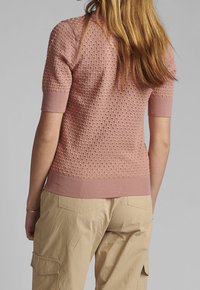 Kortärmad rosa stickad tröja med ett strukturerat mönster och ribbade ärmslut. Har en figurnära passform och en lätt design.