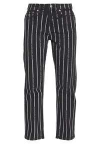 Svarta denimjeans med vertikala vita ränder och repetitiv text "CALVIN KLEIN JEANS." Femficksdesign med knappstängning.