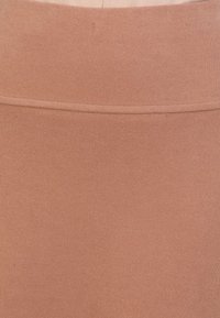 Skirt s vysokým pasem v rezavě hnědé barvě vyrobená z žebrované látky, s hladkým povrchem a jemnými vodorovnými pruhy. Jednoduchý design bez zdobení.