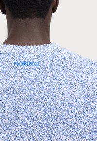 Kék és fehér kötött pulóver, textúrált mintával, kerek nyakkal és hímzett "Fiorucci" logóval a hátsó részen.